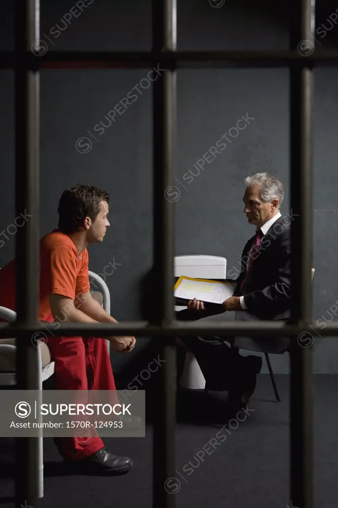A prisoner talking to a lawyer in a prison cell