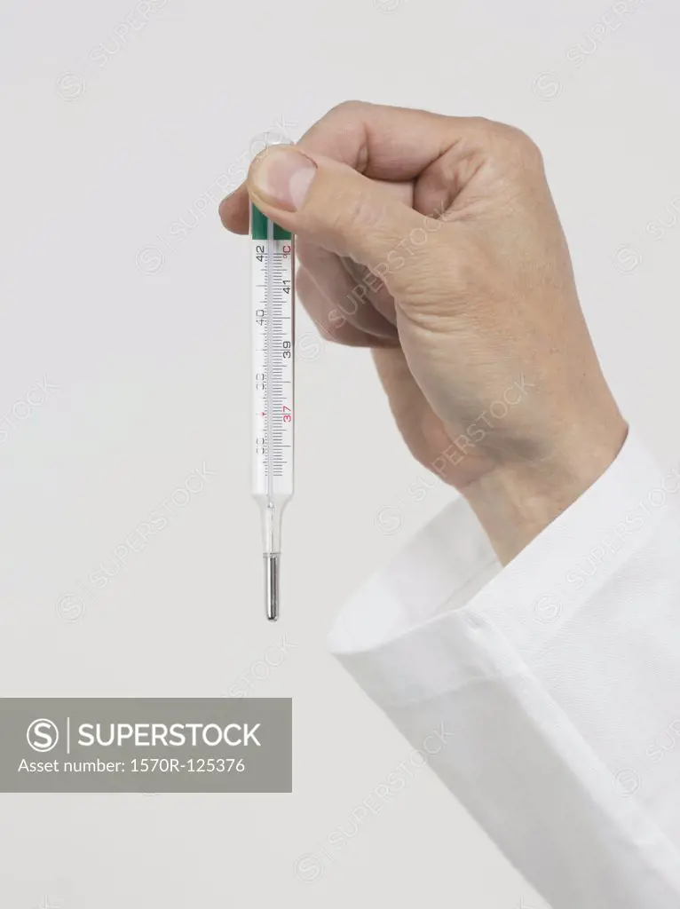 Human hand holding a thermometer