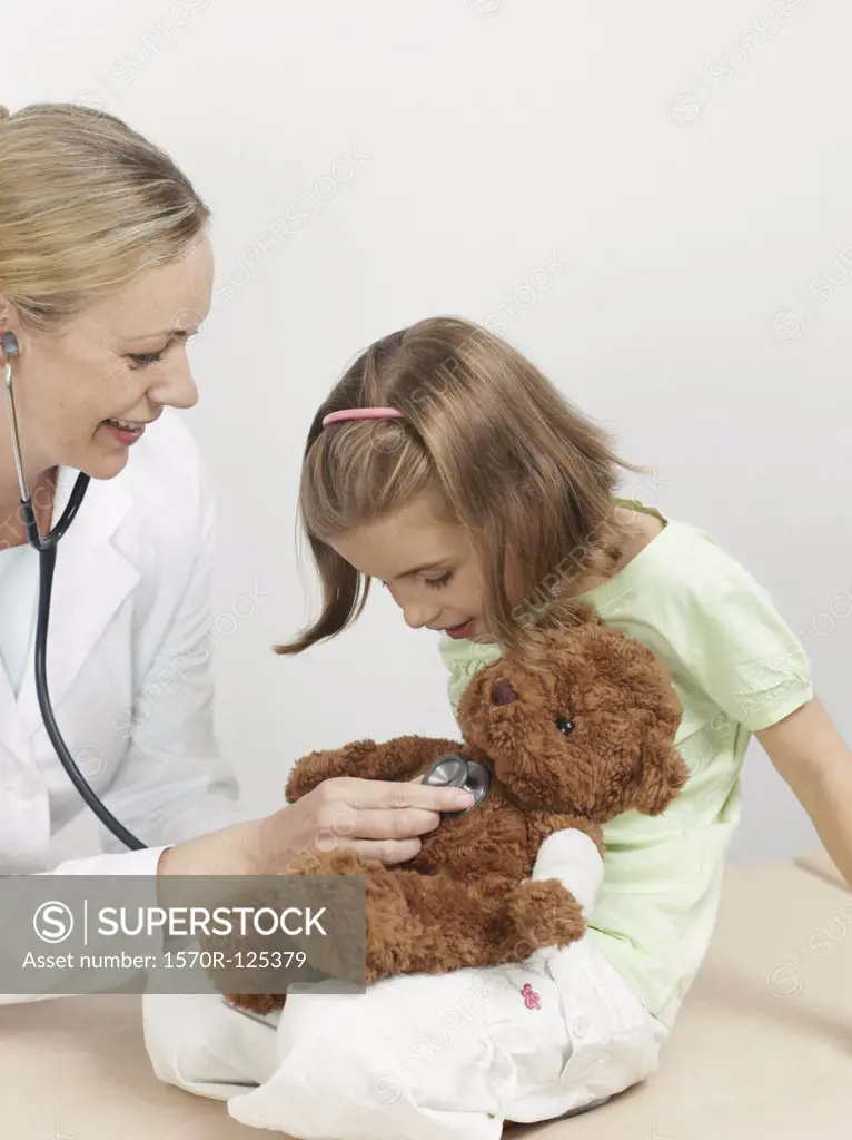 Female pediatrician examining a girl's teddy bear
