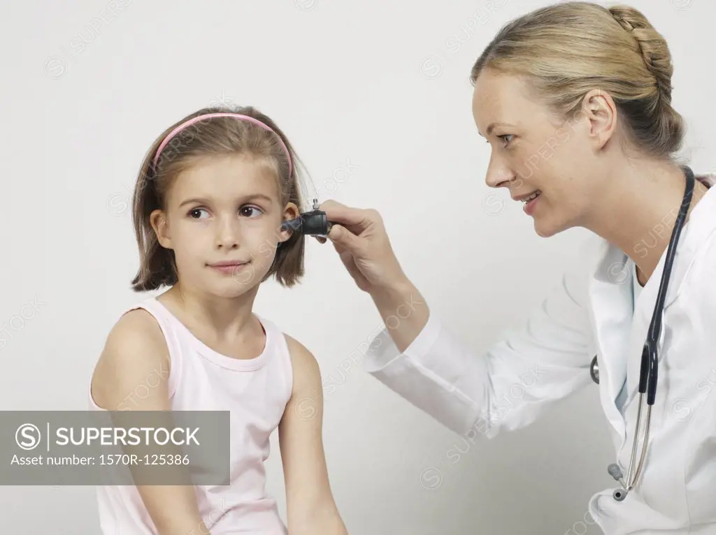 A female pediatrician using an otoscope to exam a girl's ear