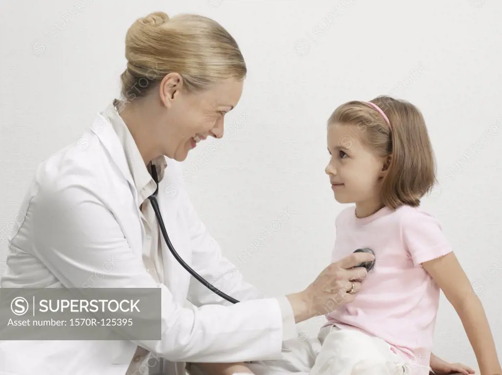 A female pediatrician putting a stethoscope on the heart of a young girl