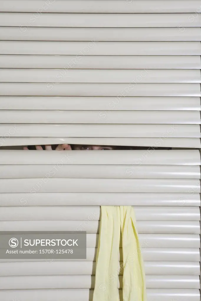 A person peeking through window blinds