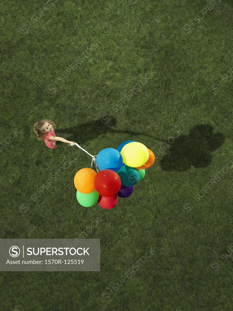 A girl holding a bunch of helium balloons
