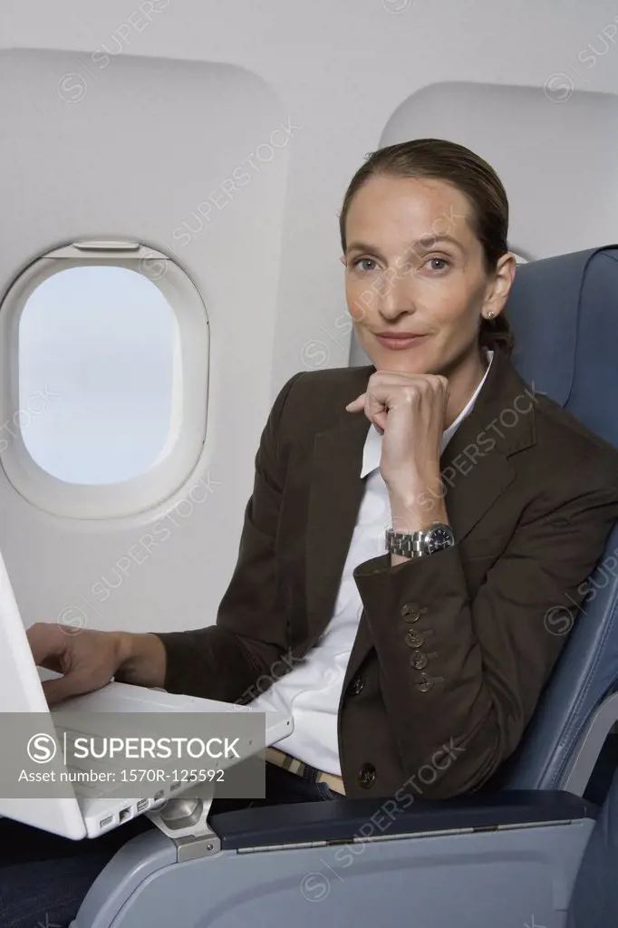 A businesswoman working on a laptop on a plane