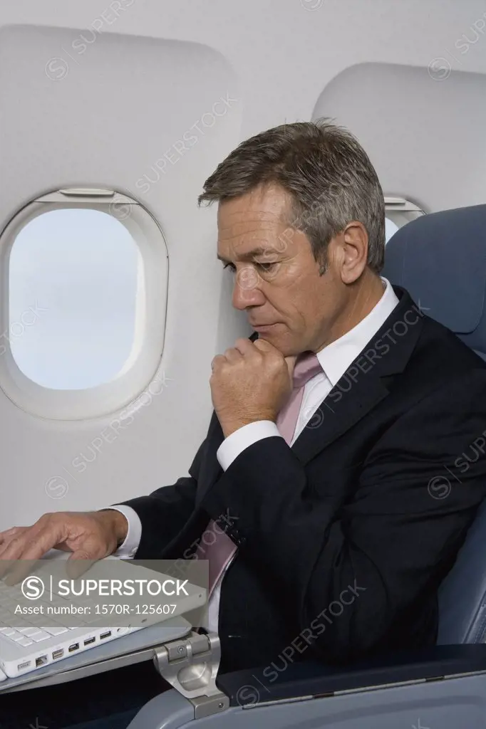 A businessman using a laptop on a plane