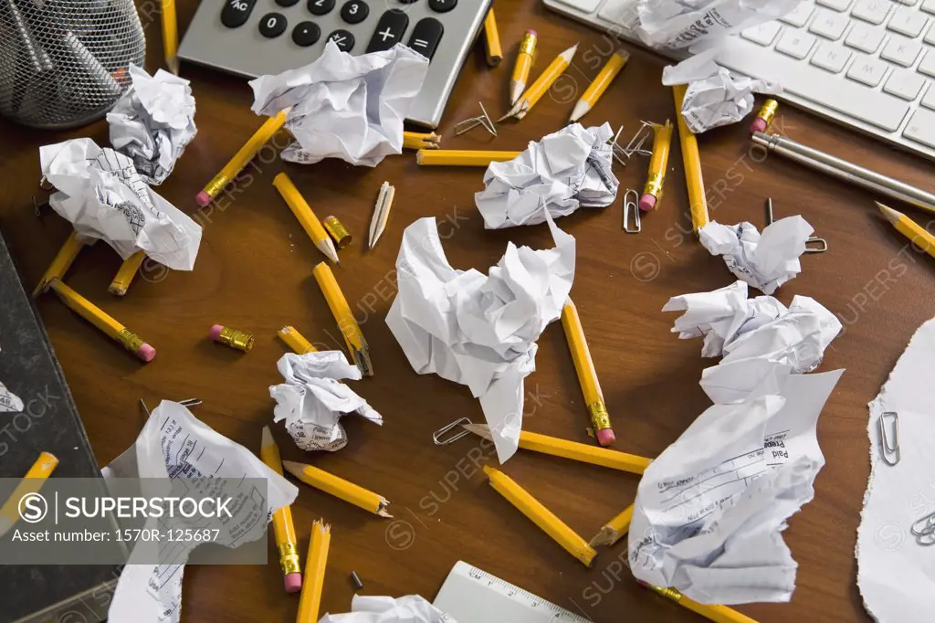 An office desk cluttered with pencils and crumpled paper