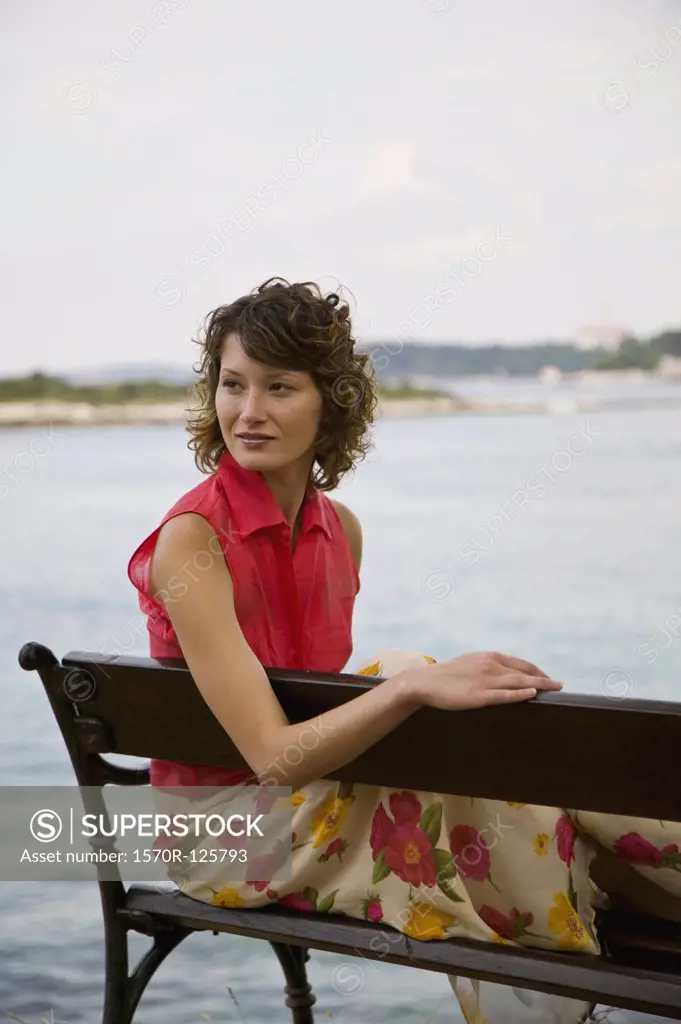 A woman sitting on a bench by the sea