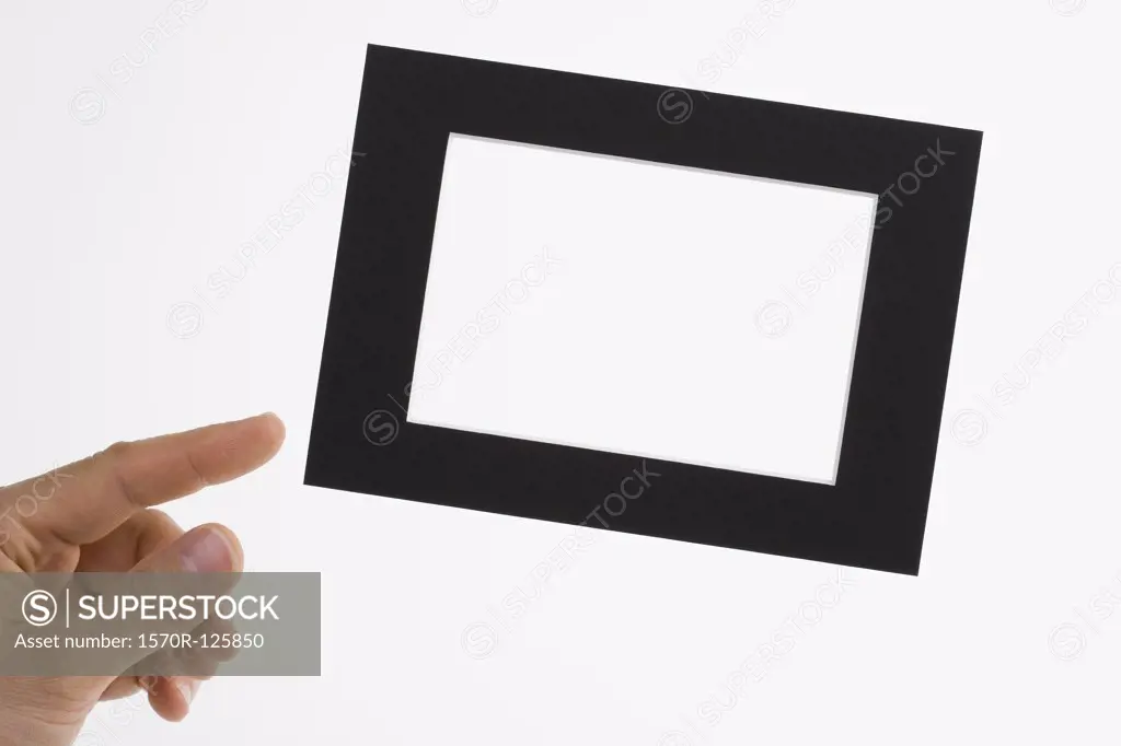 A human hand adjusting a slanted picture frame