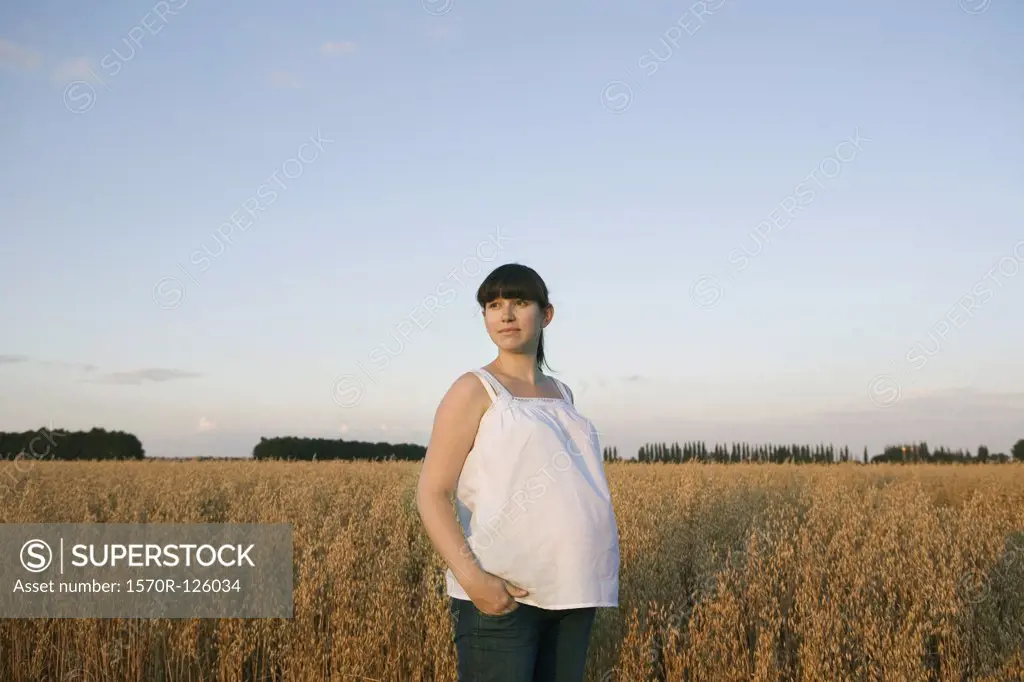 A pregnant woman standing near a wheat field