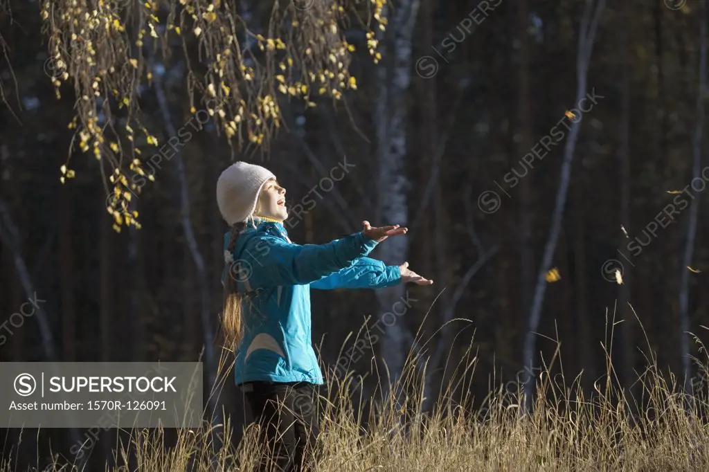 A young girl in a field catching leaves