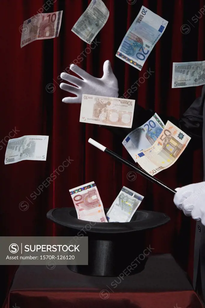 A magician performing magic by making money come out of a hat