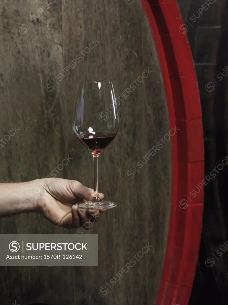 A human hand holding a glass of red wine