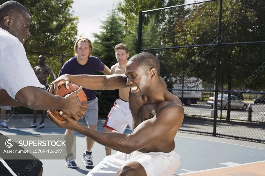 Two basketball players fighting over a basketball