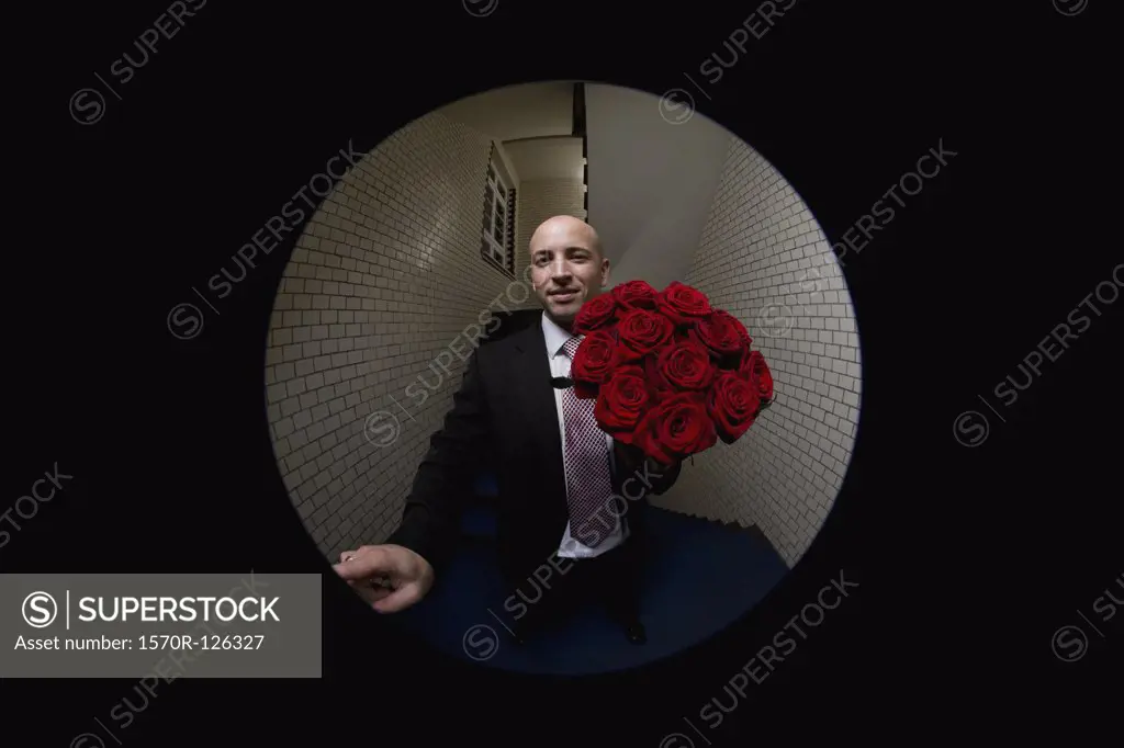 A man with a bouquet of roses pushing a doorbell, viewed through peephole