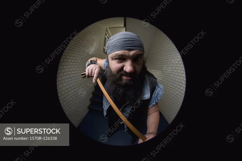 A biker breaking into a door with a crowbar, viewed through a peephole