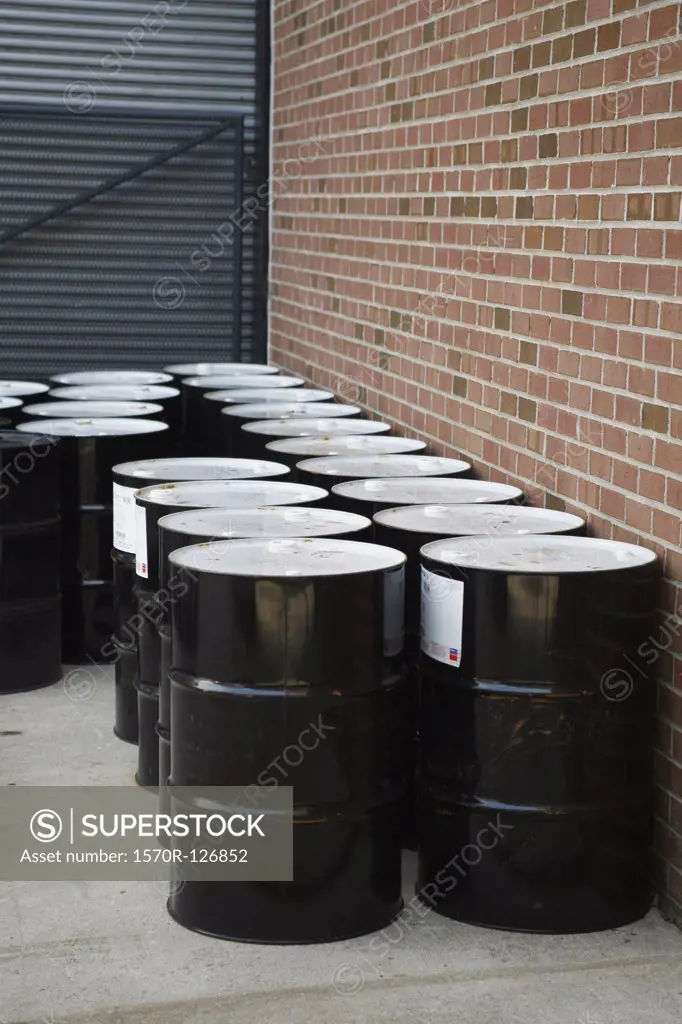 Black oil drums stacked outside a building