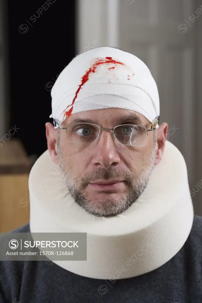 A man wearing cracked glasses, a bloody bandage on his head and a neck brace