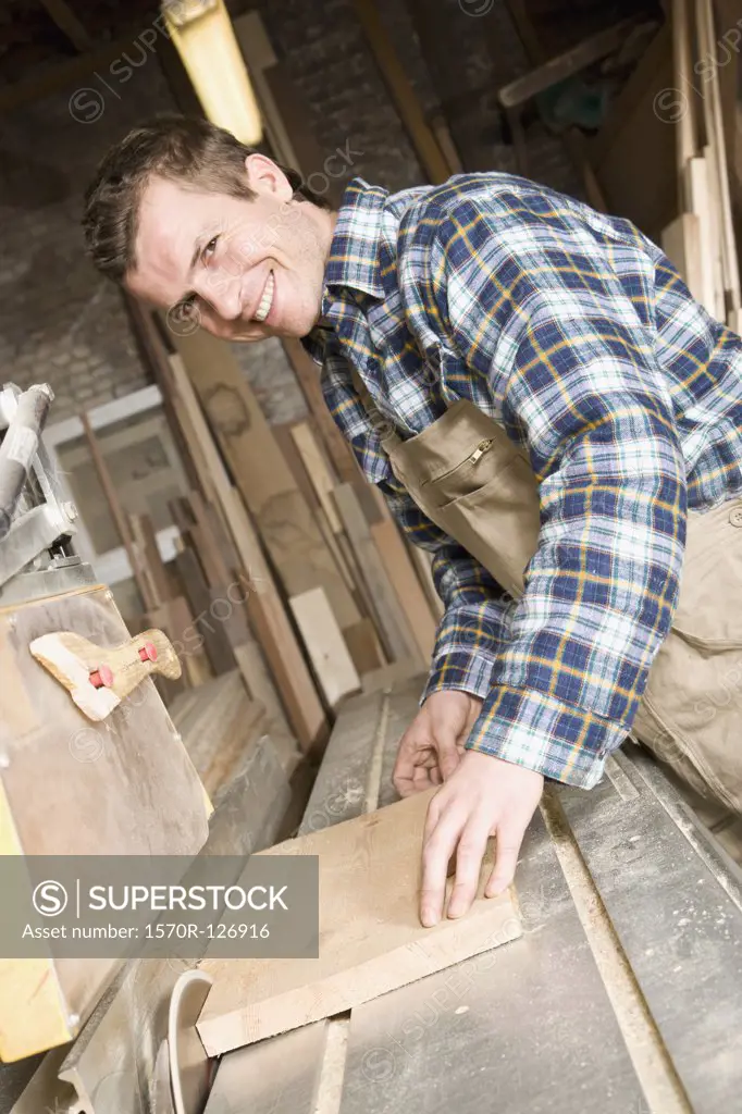 A carpenter sawing wood in a workshop
