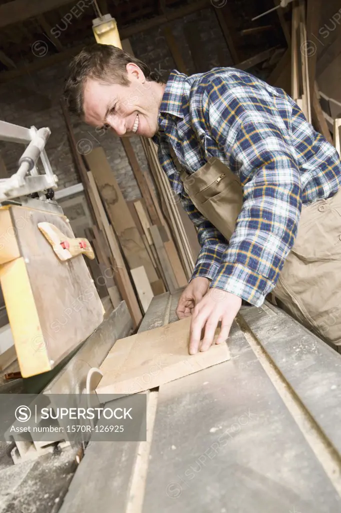 A carpenter sawing wood in a workshop