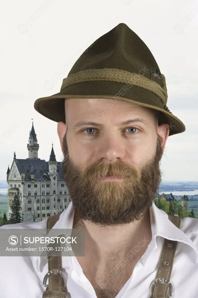 A man wearing an alpine hat and lederhosen with a backdrop of Neuschwanstein castle