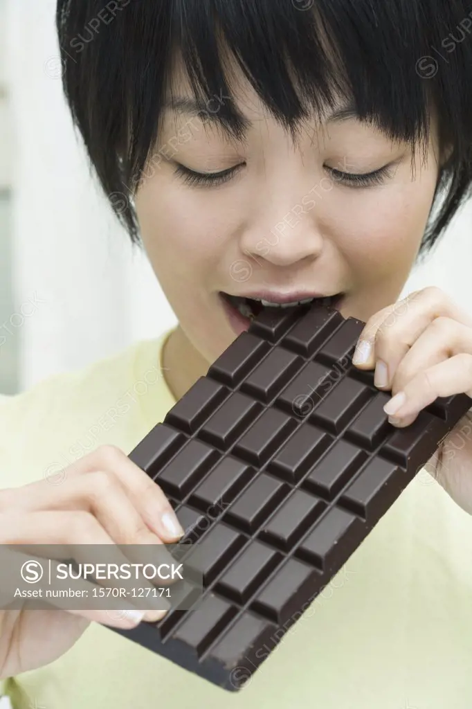 A woman biting into a chocolate bar