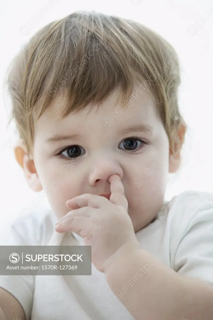 A young boy with a his finger up his nose
