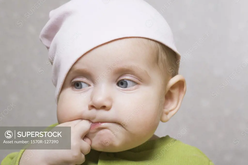 A baby girl sucking her fingers, portrait