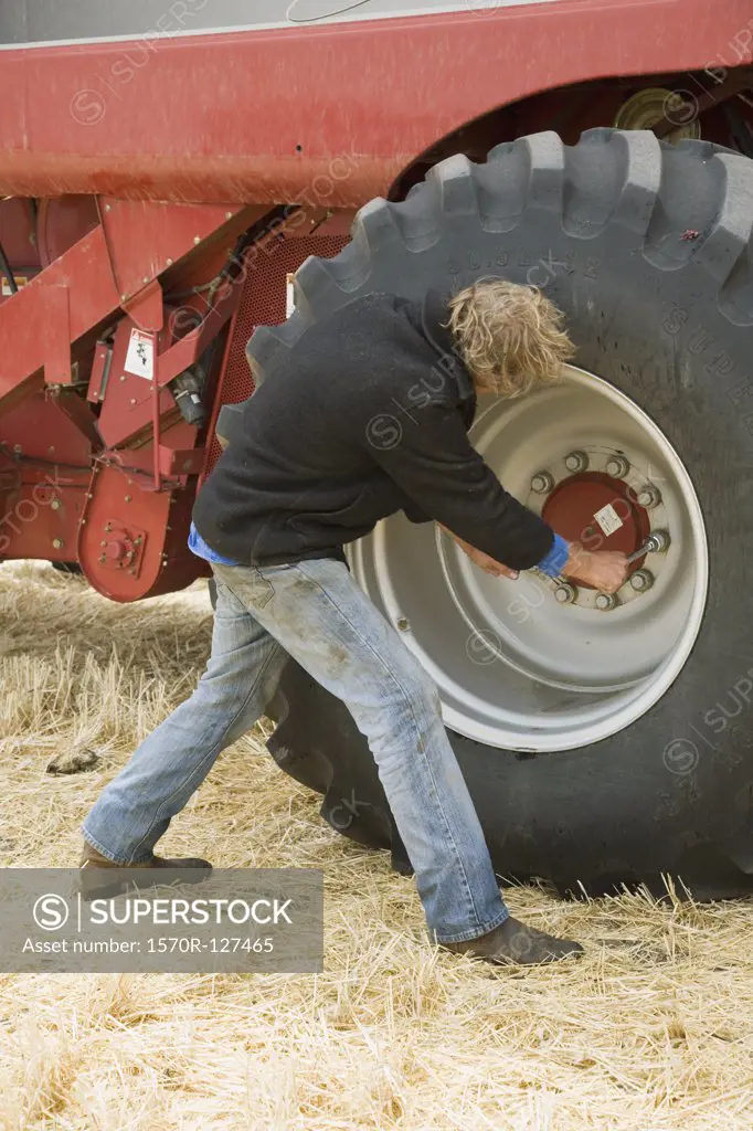 A farmer fixing the wheel of a combine