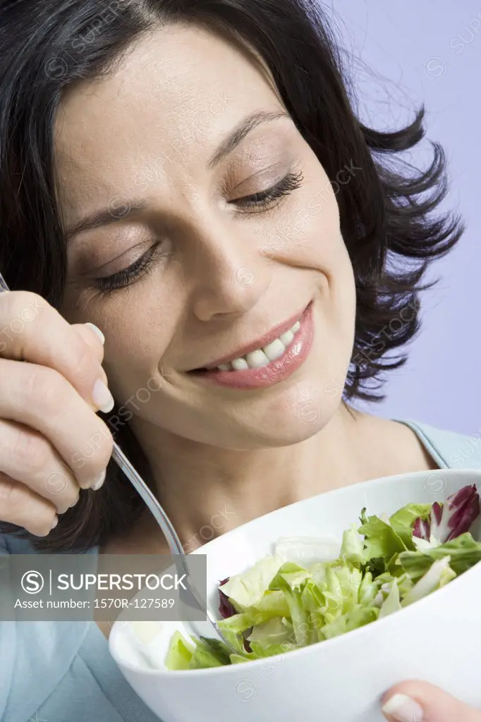 A woman eating a bowl of salad