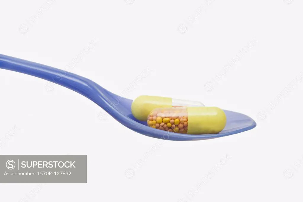 A spoon with two medicine capsules