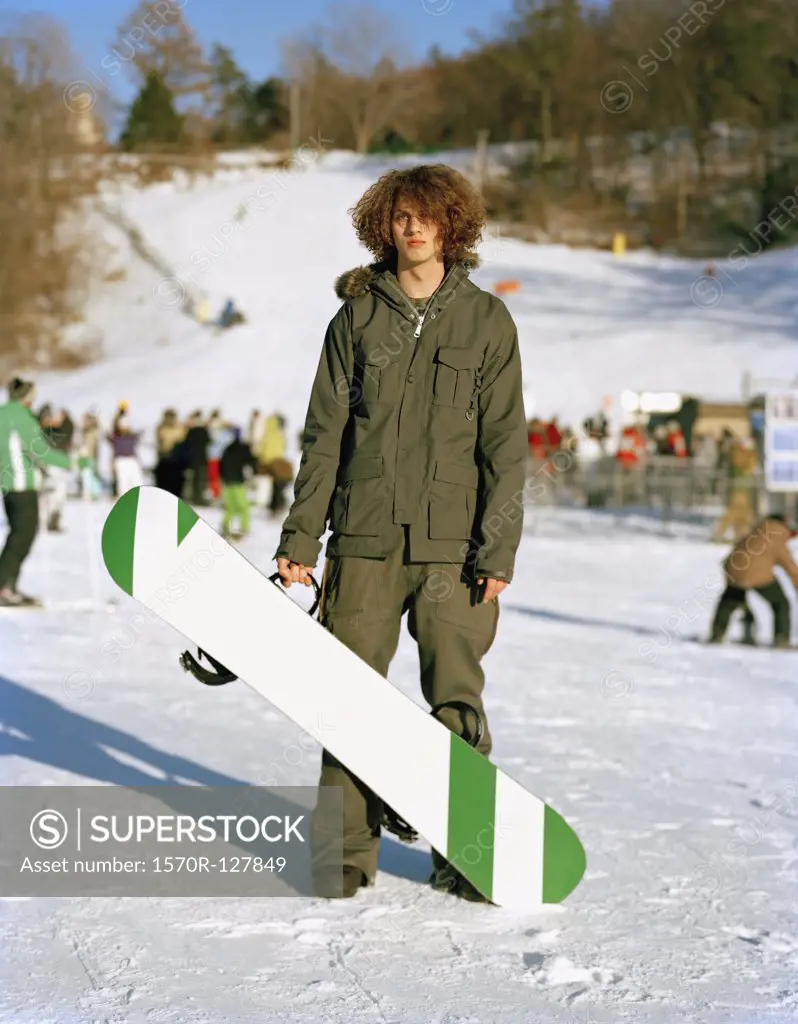 A young man standing with a snowboard at a ski resort, Mountain Creek, New Jersey, USA