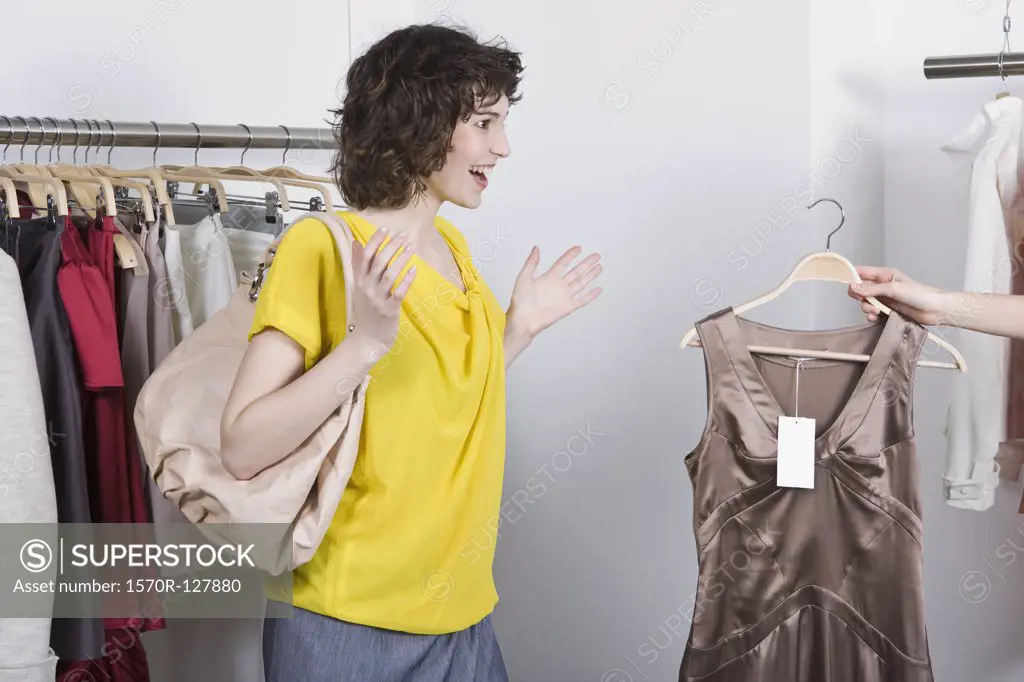 A sales assistance showing a woman a dress in a store