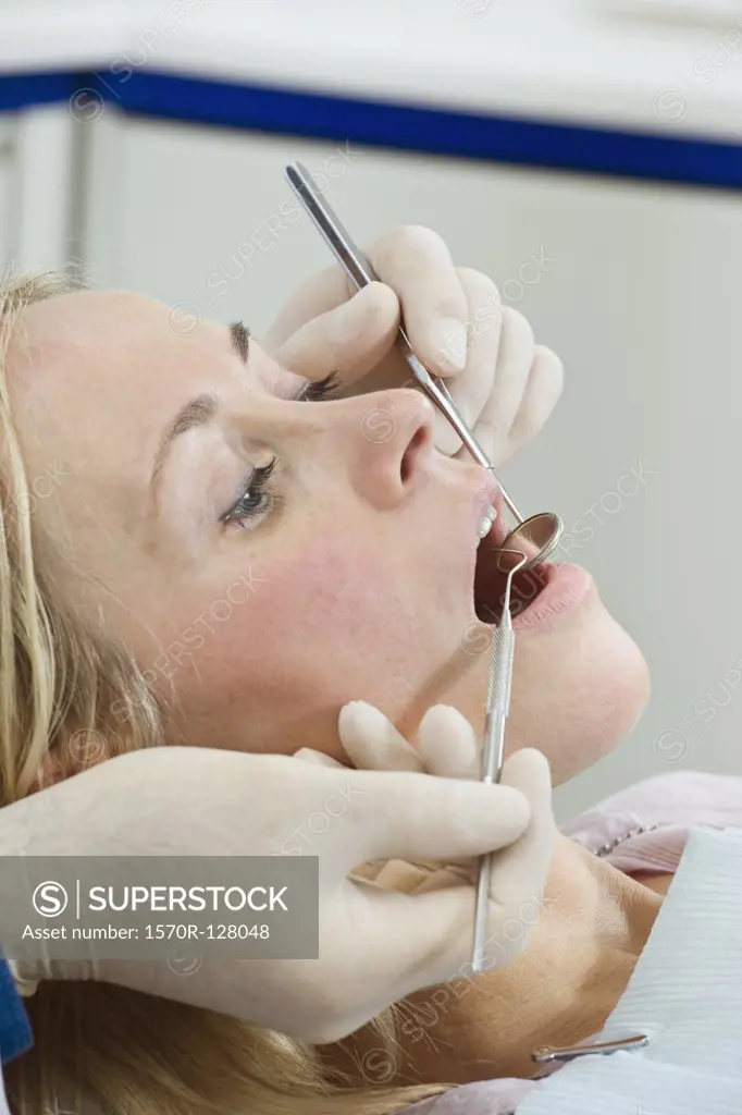 Side view of a dentist inspecting a woman's mouth