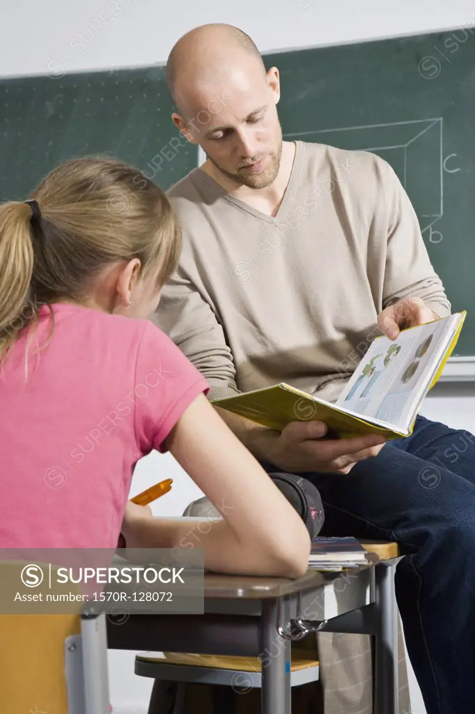 A teacher looking at a book with a student