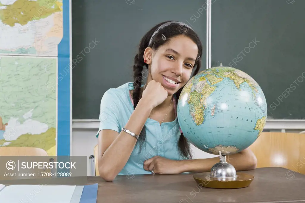 Portrait of a schoolgirl sitting near a globe