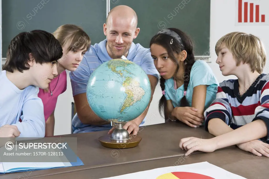 A teacher and students looking at a globe