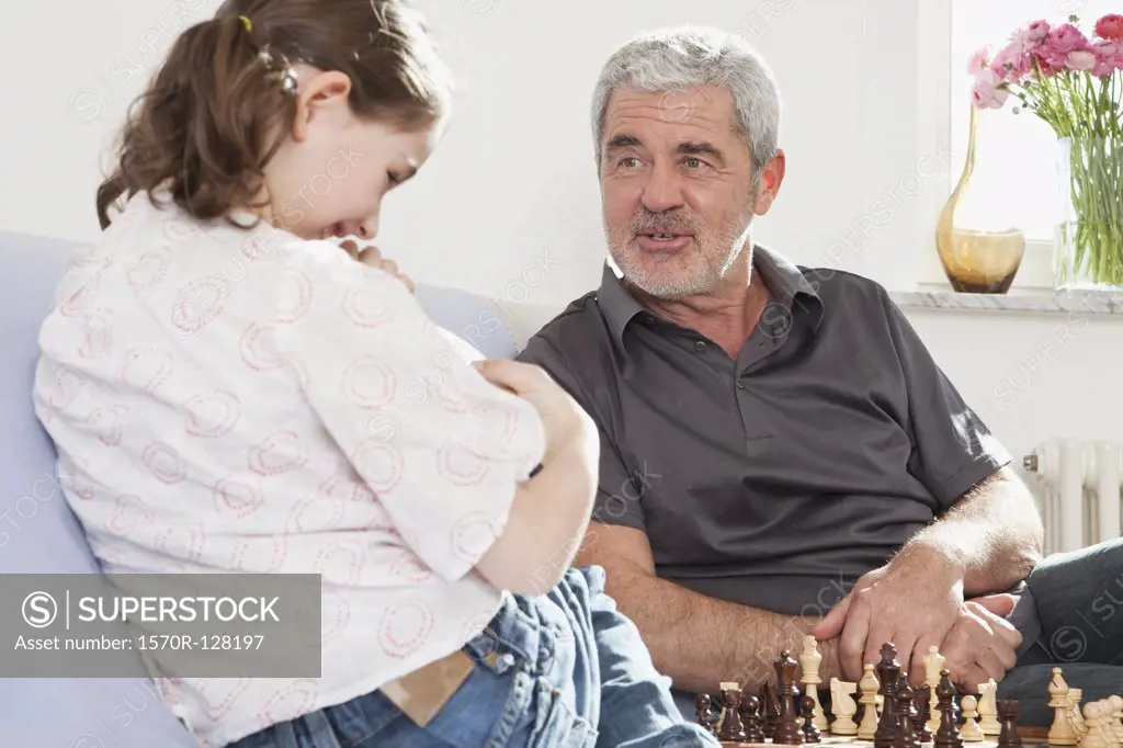 A grandfather and his granddaughter playing chess