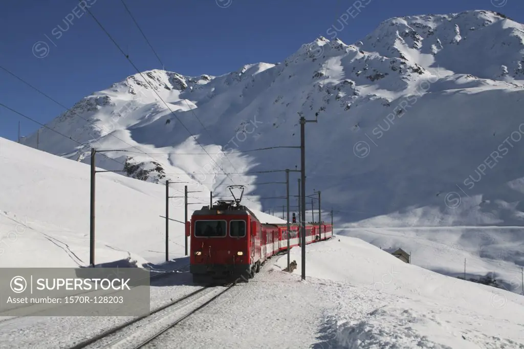 Train traveling through a mountain pass in winter, Andermatt, Uri, Switzerland