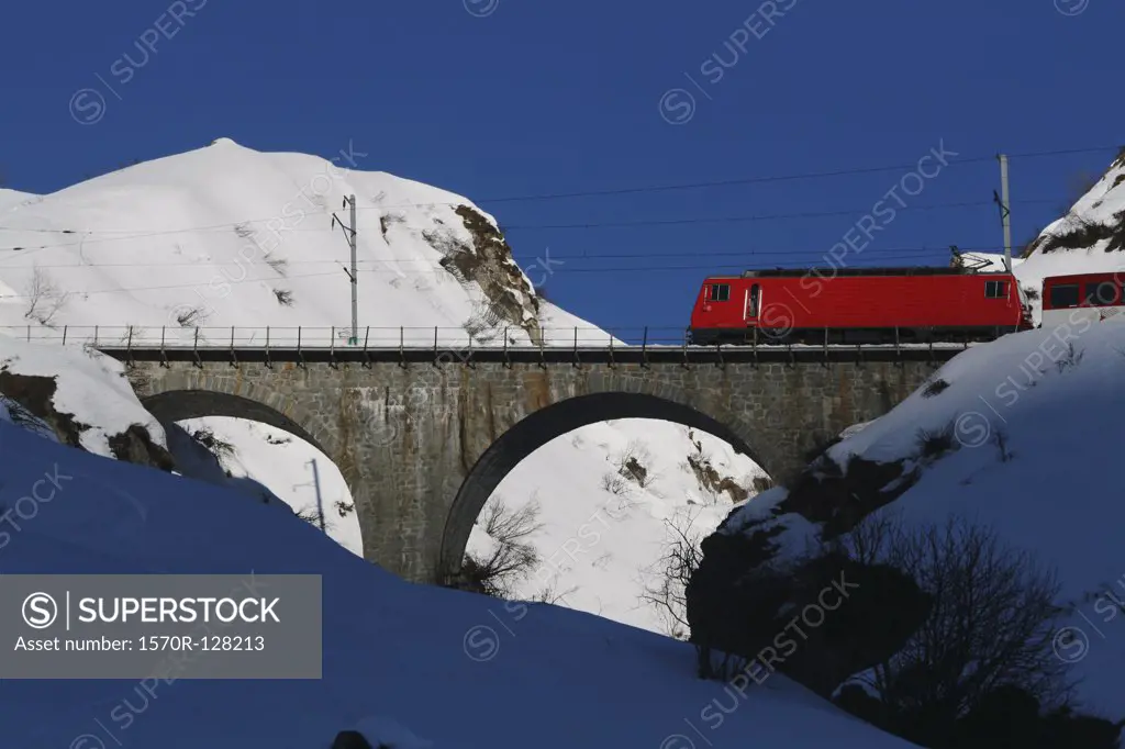 Glacier Express train crossing bridge over snowy mountains, Graubuenden, Switzerland