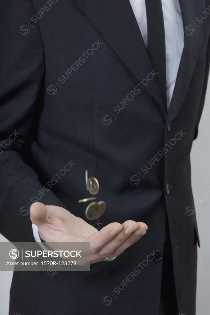 A man in a suit tossing change with his hand