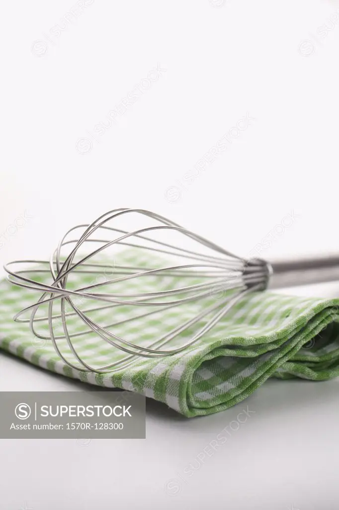 A wire whisk and checkered dish towel