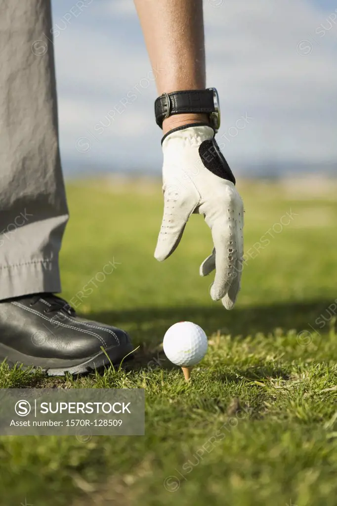 Detail of a woman putting a golf ball on a tee