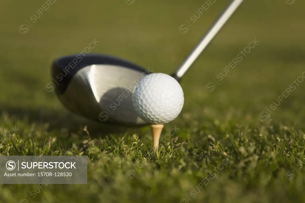 Detail of a golf club next to a golf ball on a tee