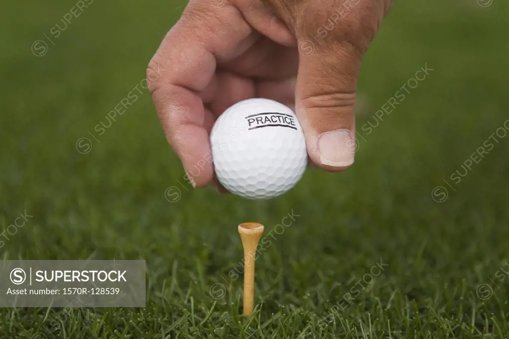 Detail of a golfer placing a golf ball on a tee