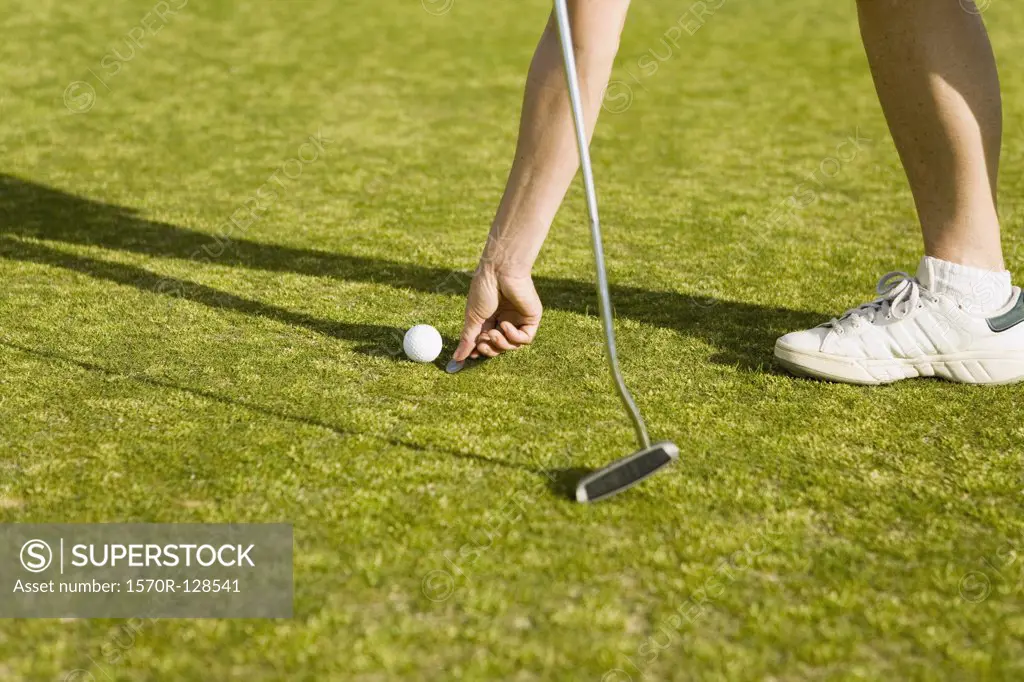 Detail of a golfer marking the ball's position with a coin