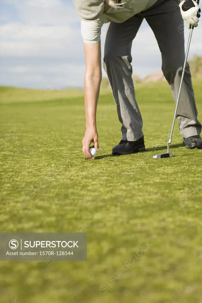 A woman putting a golf ball on a tee