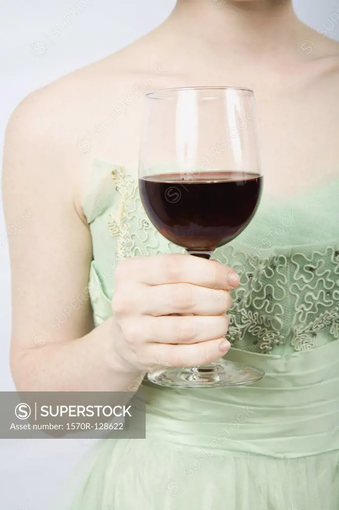 A woman wearing a vintage dress and holding a glass of red wine