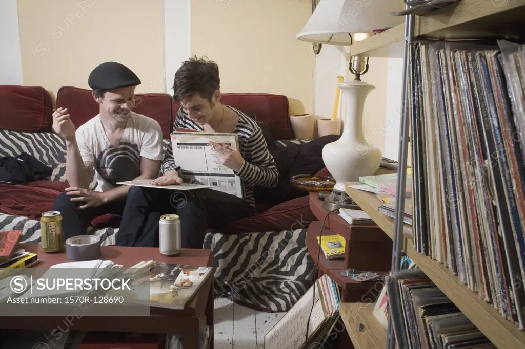Two young men looking at records on a sofa