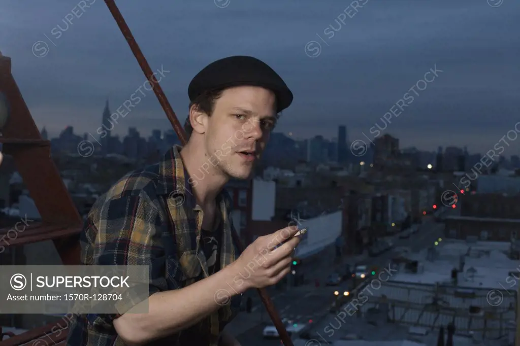 A young man standing on a fire escape smoking a cigarette