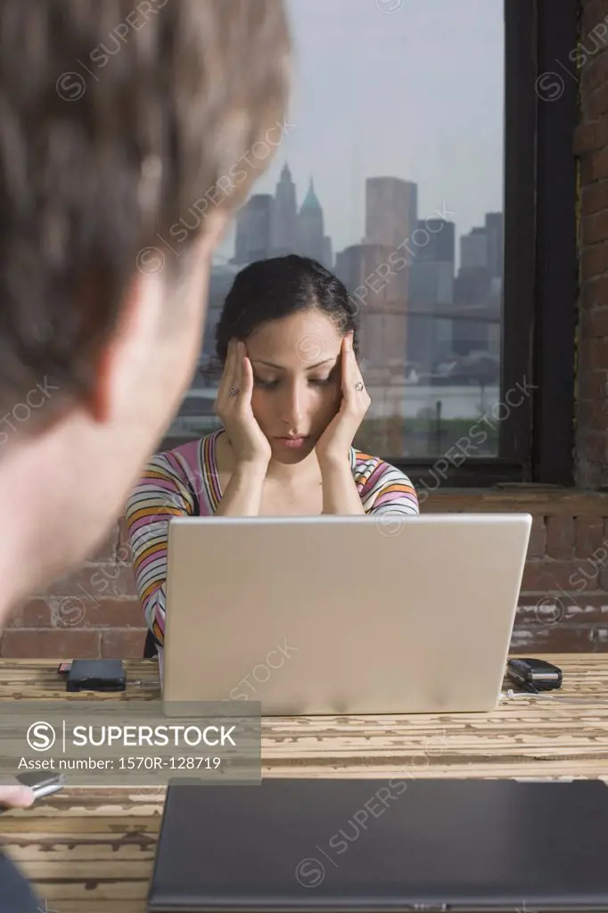Woman sitting at laptop looking stressed